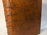an old book with a leather cover sitting on top of a white surface