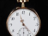 gros plan d'une montre de poche en or sur une surface noire