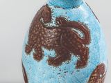 a blue vase with brown designs on it on a white surface