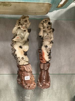 deux figurines de singes assis sur des bottes, posées sur une étagère