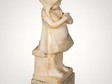 a small statue of a girl holding a bird on top of a marble block