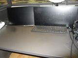 a computer desk with two monitors and a keyboard on it