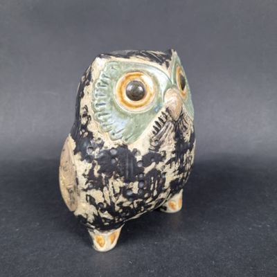 une petite figurine de chouette posée sur une surface noire