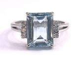 a close up of a ring with an aquamarine stone and diamonds