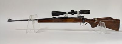 le fusil est posé sur un support transparent et est équipé d'une lunette de visée