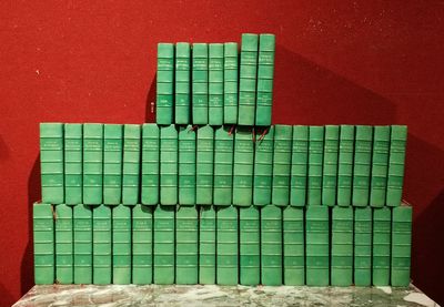 des livres empilés les uns sur les autres sur une table devant un mur rouge