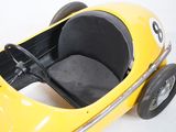 a yellow pedal car with a black seat on it