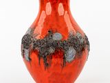 a red vase with black spots on it on a white surface