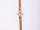 une image d'une montre-bracelet en or sur une surface blanche