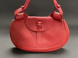 a red leather purse with a metal clasp on the handle