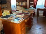 un bureau sur lequel sont posés de nombreux livres, dans une pièce