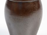 a brown vase that is sitting on a white surface
