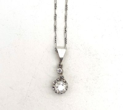 un gros plan d'un pendentif en diamant suspendu à une chaîne, posé sur une surface blanche
