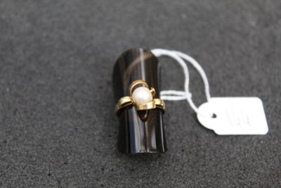 an image of a ring with a pearl on it sitting on top of a piece of wood
