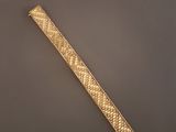 gros plan d'un bracelet en or sur une surface grise