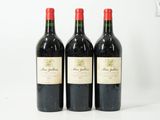 trois bouteilles de vin rouge sont alignées sur une surface blanche