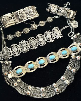 plusieurs bijoux en argent et en turquoise posés sur un fond noir