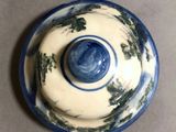 a close up of a blue and white bowl with trees on it