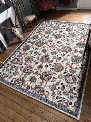une photo d'un tapis dans une pièce avec une cheminée et un fauteuil