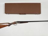 un vieux fusil et une boîte posés sur une surface blanche