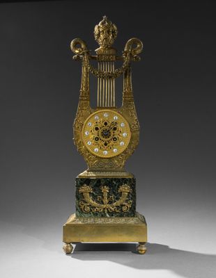 une horloge dorée et verte posée sur un socle, sur une surface grise