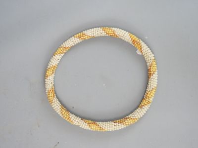 a close up of a white and yellow beaded bracelet on a table