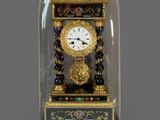 une petite horloge sous un dôme de verre sur une table
