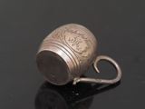 a silver cup with a handle on a black surface