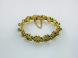 a gold bracelet with green stones