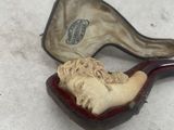 a pipe with a man ' s face in it sitting in a case