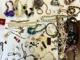 beaucoup de bijoux posés sur une table, à côté d'une paire de ciseaux