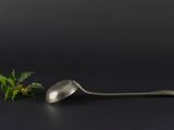 a spoon and a sprig of mint on a black background