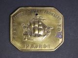 brass plate with a picture of a ship on it on a black surface