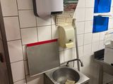 un lavabo dans des toilettes publiques, avec un distributeur de papier accroché au mur