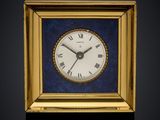 a small square clock with roman numerals in a gold frame