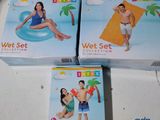 trois boîtes de « wet set » posées sur une table, en présence d'une femme en maillot de bain et d'un homme en maillot de bain