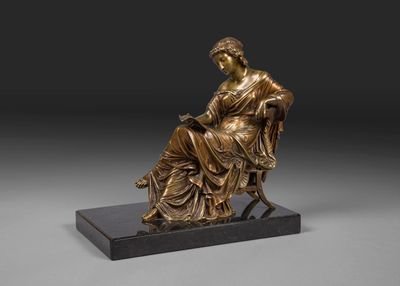 une statue en bronze représentant une femme assise sur une chaise