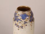 a white vase with blue flowers on it on a table