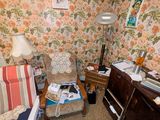 une pièce avec un bureau, une chaise, une lampe et des tableaux accrochés au mur
