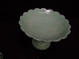 a green bowl sitting on top of a black table