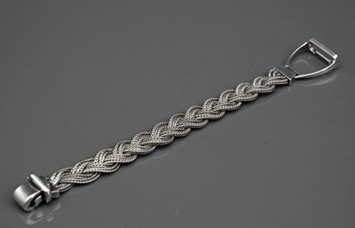 un gros plan d'un bracelet en argent posé sur une surface grise