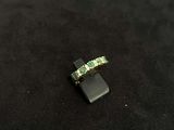 a close up of a ring with three emerald stones on a black surface