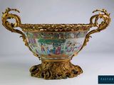 un grand vase décoré, muni d'une anse dorée et posé sur un socle