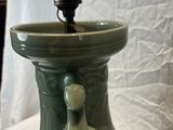 a green vase that has a light on top of it