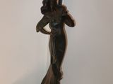 a statue of a woman holding a lamp on a table