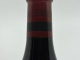 the bottle of red wine is sitting on a white surface
