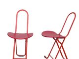 pair of red metal folding chairs on a white background