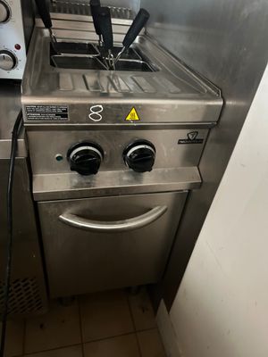 une cuisinière argentée sur laquelle sont posés une friteuse et un grille-pain