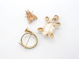 two gold brooches and a broochle on a white surface