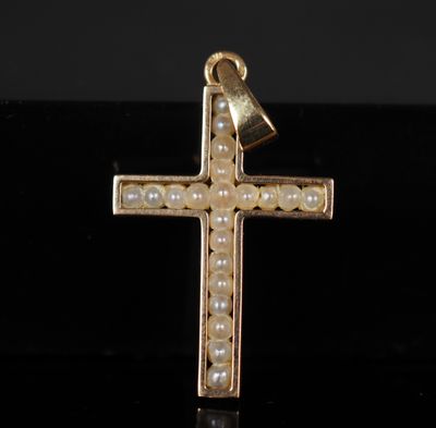 un gros plan d'une croix en or ornée de perles sur un fond noir